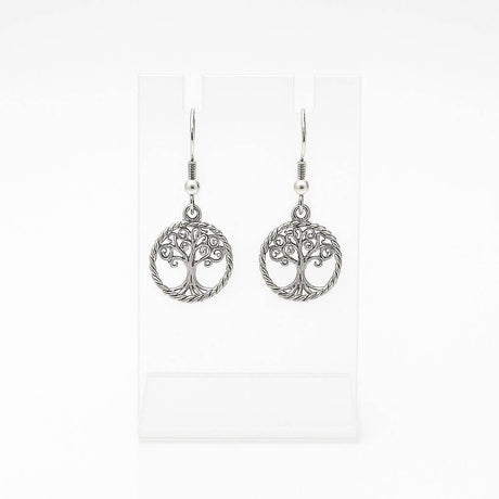 The Tree of Life Round Drop Silver Earrings feature handcrafted round silver dangle designs, shown on a clear stand with a white background.