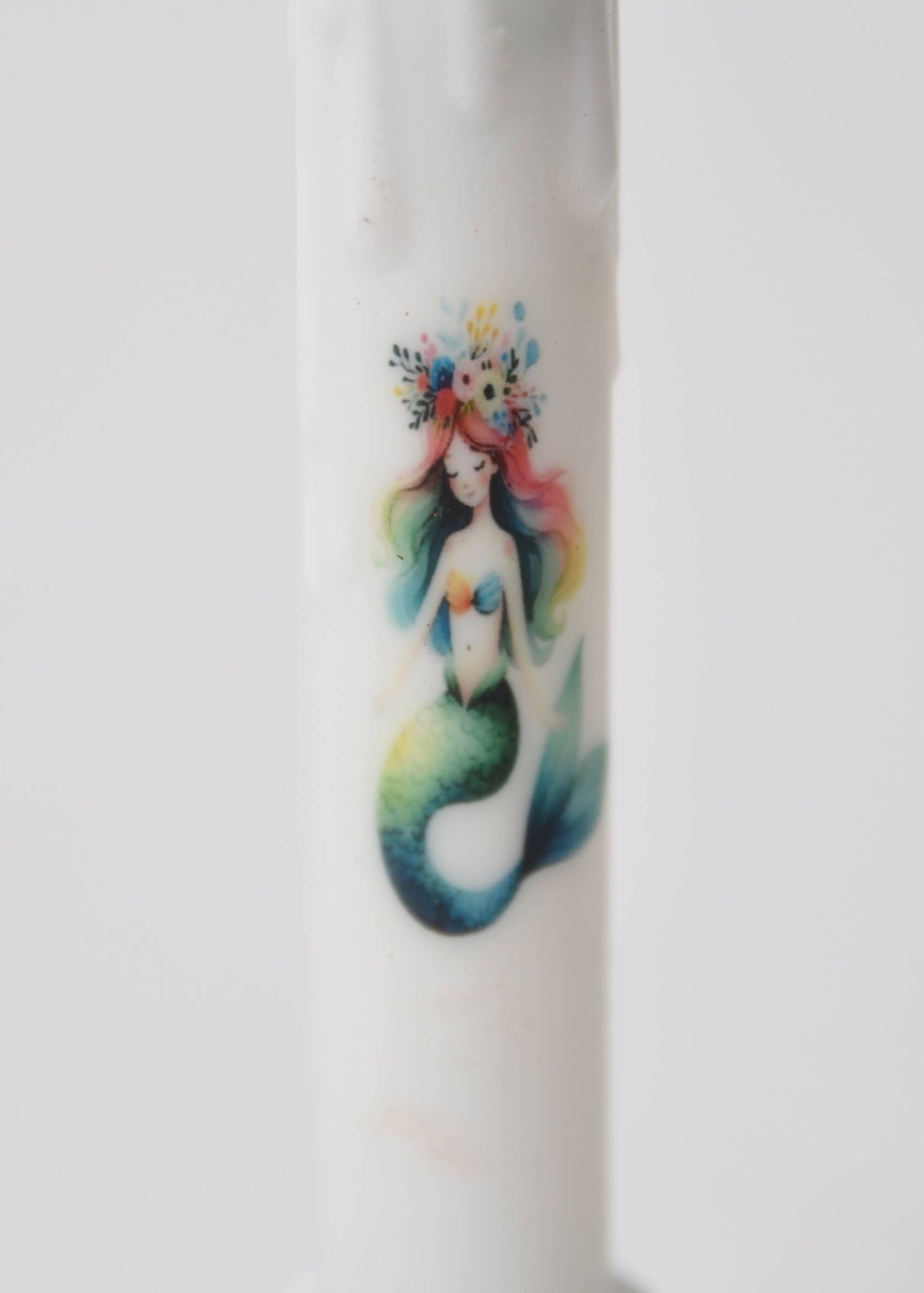 The Candle: Mermaid LED Timer Taper Candle features a vibrant mermaid with rainbow hair and a floral crown, bringing whimsical charm to any space.