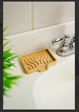 Soap holder with carved grooves on a white sink, positioned beside a silver faucet and a small green plant.