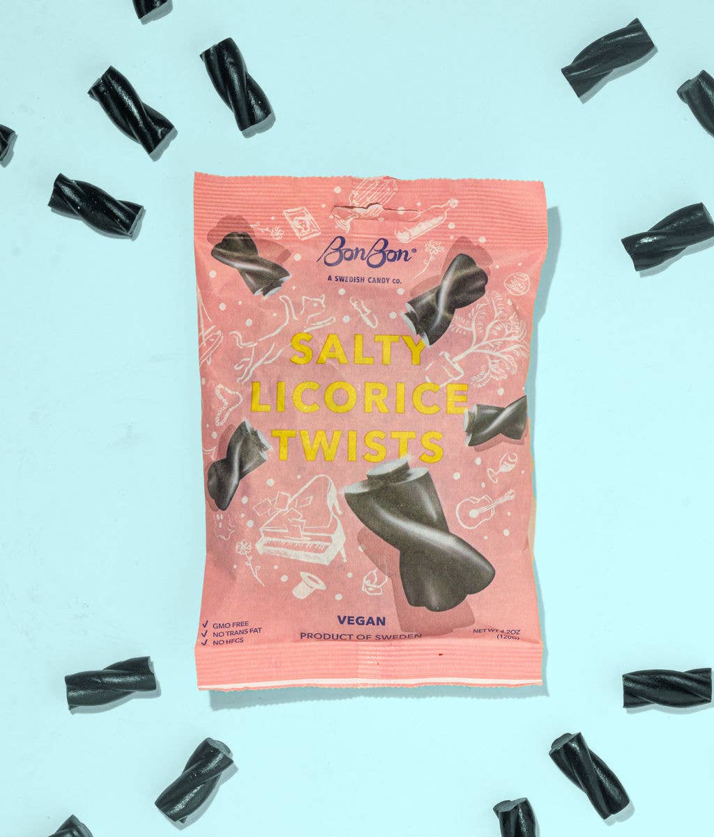 A pink package of BonBon Candy: Salty Licorice Twists (120g), a popular Swedish treat, lies on a light blue backdrop with pieces of black licorice scattered around. The packaging highlights the twists as vegan and made in Sweden.