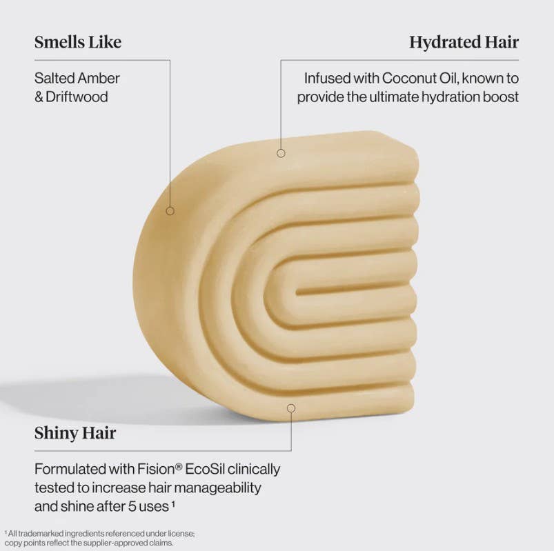 A beige, curved KITSCH Coconut Oil Hair Conditioner Bar for Dry Damaged Hair (2.7oz) is shown. Text highlights its salted amber and driftwood scent, hydrating coconut oil, and Fision® EcoSil for noticeably shinier hair after five uses. This moisturizing conditioner from KITSCH is especially suitable for curly hair, leaving your locks soft, defined, and beautifully fragranced.