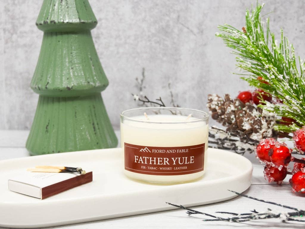 The Candle: Father Yule Premium Soy Candle by Fjord & Fable (4oz jar, 2 wicks, 20+ hour burn) sits on a tray with a matchbox and festive decor—ideal for bringing a warm Yuletide scent to your holiday gatherings.