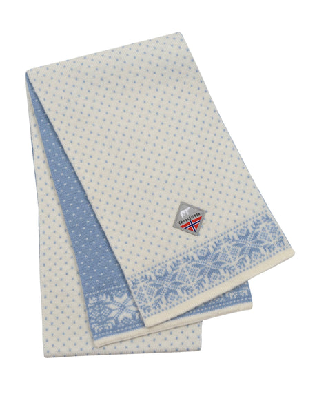 The Scarf: Snowflake Norwegian Wool White and Blue Scarf features geometric patterns and a small sewn Norwegian flag patch, capturing the traditional charm of Norwegian knitwear.