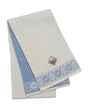The Scarf: Snowflake Norwegian Wool White and Blue Scarf features geometric patterns and a small sewn Norwegian flag patch, capturing the traditional charm of Norwegian knitwear.