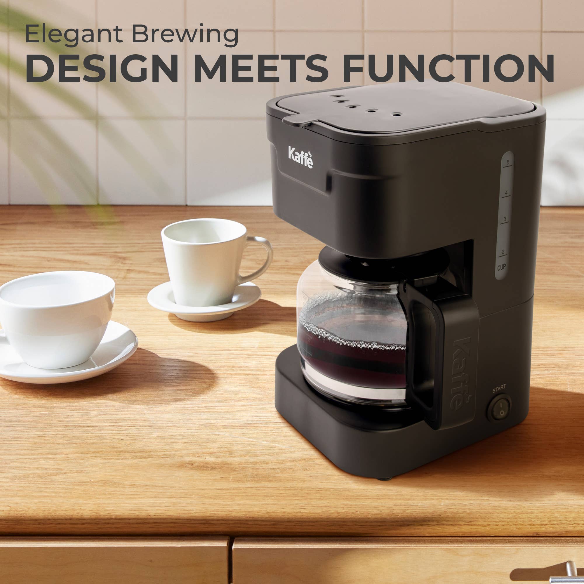 The Kaffe 5-Cup Coffee Maker w/ Scoop - Black, featuring a reusable filter basket and glass carafe, sits on a kitchen counter beside two white cups; text reads “Elegant Brewing DESIGN MEETS FUNCTION.”.