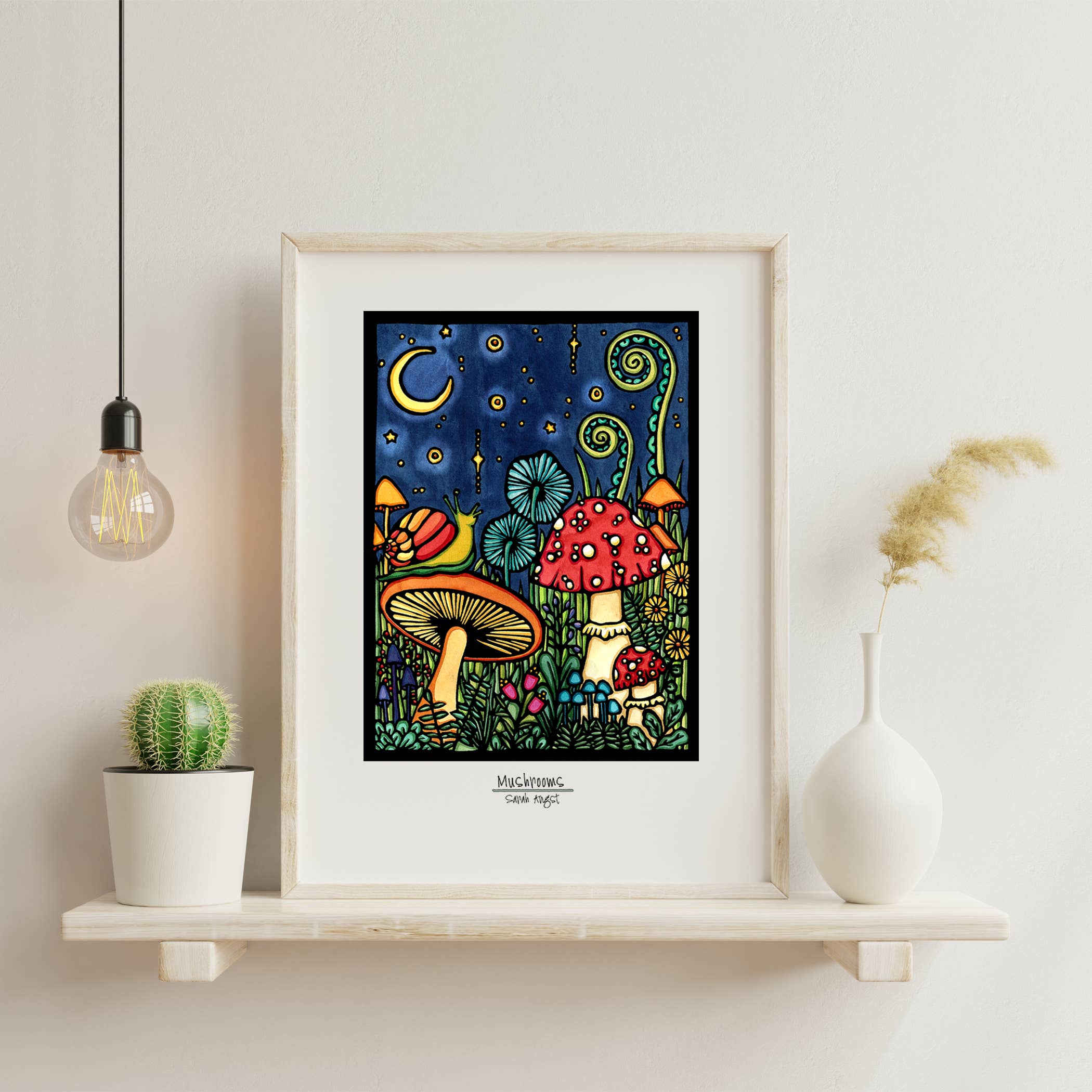 The 11"x14" Framed Black Mushroom artwork, featuring colorful mushrooms under a starry night sky with a crescent moon, is beautifully displayed on a wooden shelf alongside a bulb, small cactus, and white vase.