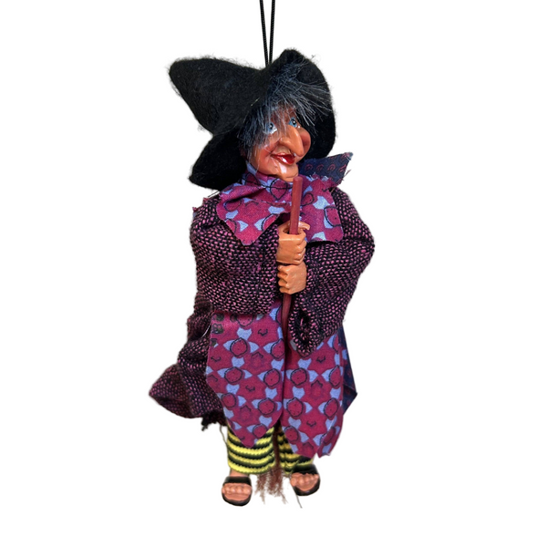 The Figurine: Johanna – Purple Kitchen Witch Doll (9" Tall) features a black hat, purple patterned clothes, and yellow-striped socks, holding a broomstick—a whimsical Scandinavian folk-inspired good luck charm.