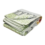 Folded Swedish design blanket featuring a green, gray, and white snowflake pattern on a plain white background.