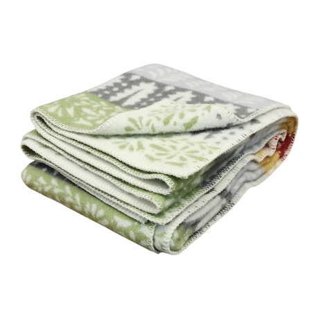 Folded Swedish design blanket featuring a green, gray, and white snowflake pattern on a plain white background.