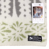 Patterned wool throw with green and gray designs, rectangular label, and product tag attached; Swedish design visible on soft woven surface.