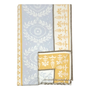 Folded lambswool blanket featuring blue and yellow sections, white floral and geometric patterns, and brown stitched edges.