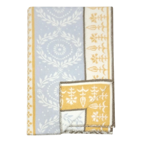 Folded lambswool blanket featuring blue and yellow sections, white floral and geometric patterns, and brown stitched edges.