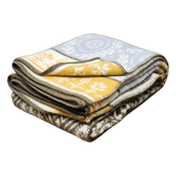 Folded lambswool blanket featuring yellow, white, and brown floral patterns with dark brown stitched edges, displayed on a white background.