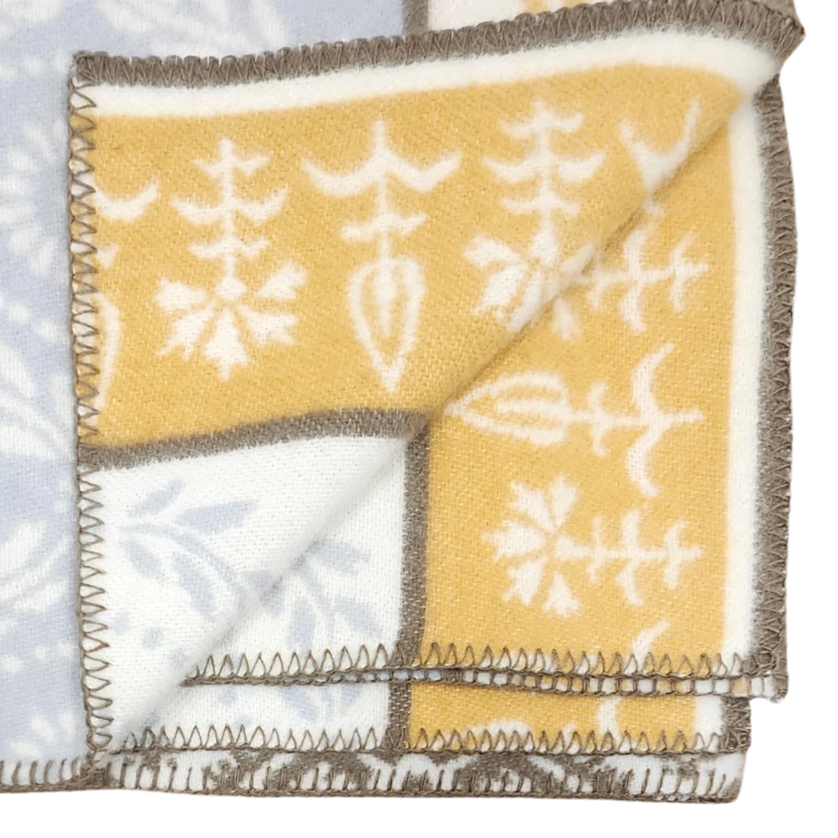 Folded Swedish wool blanket with a yellow and white botanical pattern on one side, pale blue reverse, and dark stitched edges.