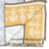 Folded Swedish wool blanket with a yellow and white botanical pattern on one side, pale blue reverse, and dark stitched edges.
