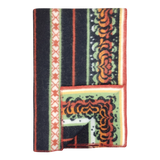 Bunad blanket with orange, black, green, and cream stripes, floral patterns, contrasting borders, and a turned-up corner showing the underside.