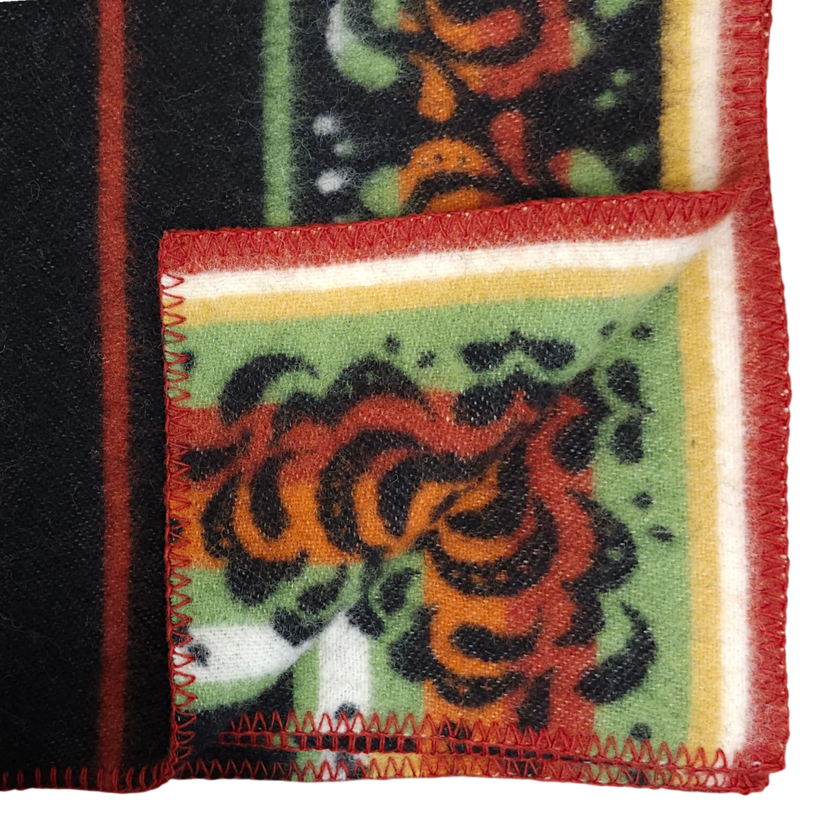Folded Bunad blanket with red, orange, and green floral patterns, yellow and white stripes, and red zigzag stitching along the edge.
