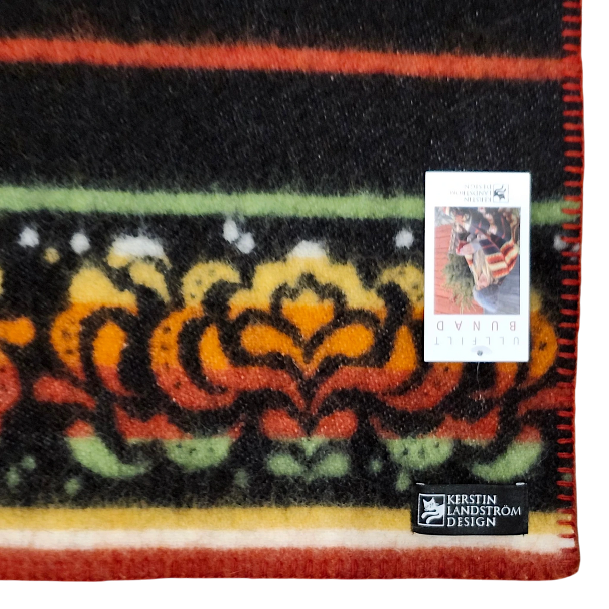 Close-up of a lambswool blanket with a visible Kerstin Landstrom Design label and a product tag displaying a cat photo and corner text.
