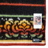 Close-up of a lambswool blanket with a visible Kerstin Landstrom Design label and a product tag displaying a cat photo and corner text.