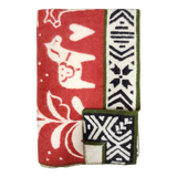 Folded red and white lambswool blanket featuring animal, heart, and geometric patterns, Swedish Dala horses, and green trim.