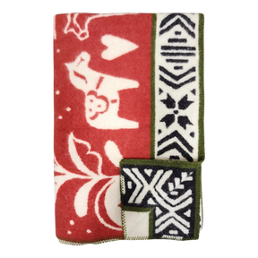 Folded red and white lambswool blanket featuring animal, heart, and geometric patterns, Swedish Dala horses, and green trim.