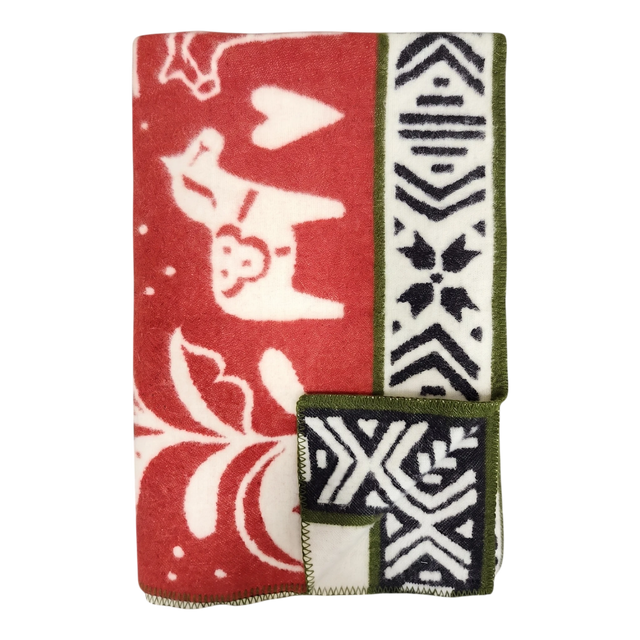 Folded red and white lambswool blanket featuring animal, heart, and geometric patterns, Swedish Dala horses, and green trim.