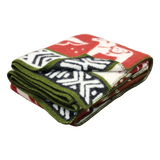 Folded fleece blanket in red, green, white, and black with geometric shapes and animal motifs, including a prominent white bear.