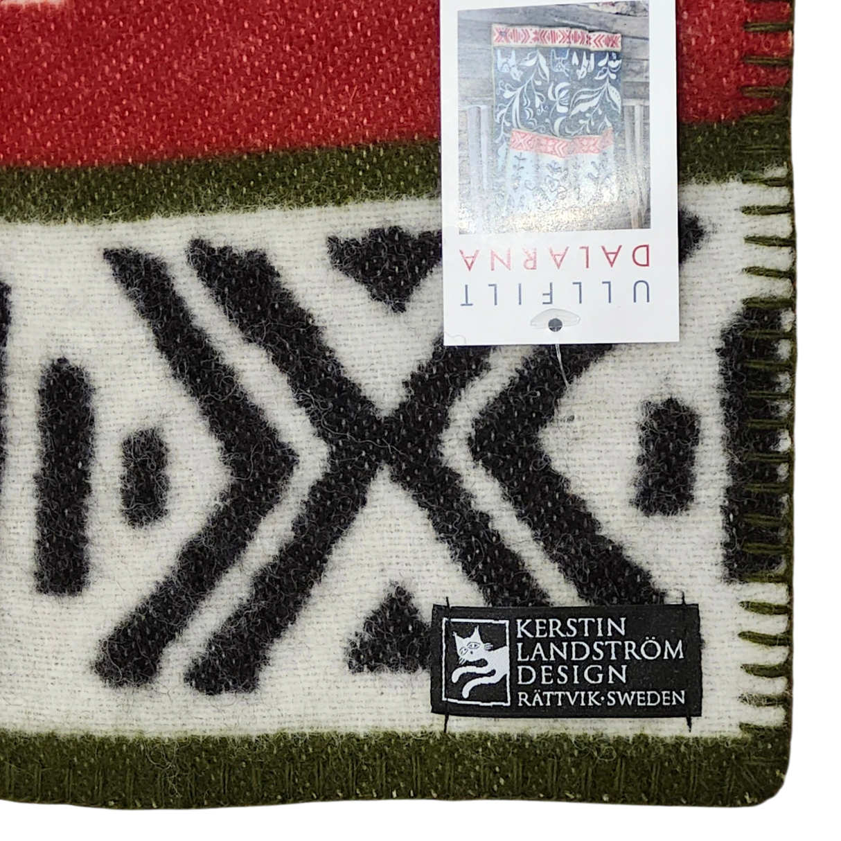 Lambswool blanket featuring black geometric patterns, red and green stripes, Swedish Dala Horses, and two visible tags including one labeled Kerstin Landström Design.