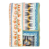 Folded fleece blanket with green trim, orange floral and blue geometric patterns on a cream background, showing Swedish-inspired design.