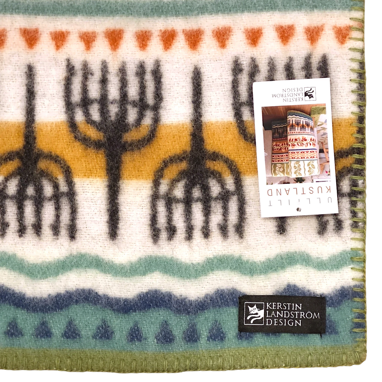 Lambswool blanket featuring rows of black trees, orange and teal stripes, a visible Kerstin Landström Design label, and product tag; Swedish design.