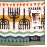 Lambswool blanket featuring rows of black trees, orange and teal stripes, a visible Kerstin Landström Design label, and product tag; Swedish design.