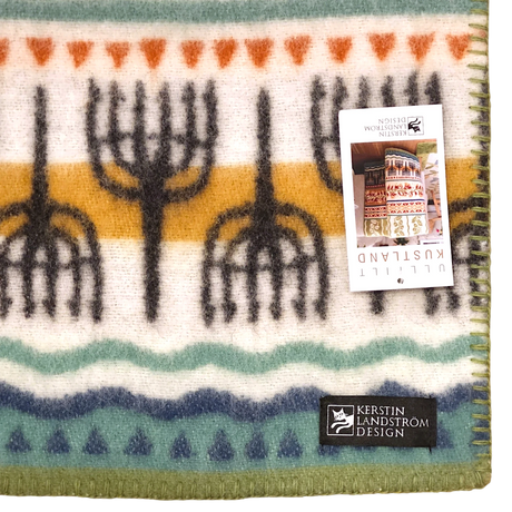 Lambswool blanket featuring rows of black trees, orange and teal stripes, a visible Kerstin Landström Design label, and product tag; Swedish design.