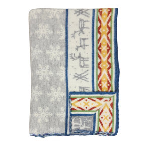 Folded Sámi-inspired wool blanket featuring a gray snowflake pattern, blue border, and one side with geometric and stripe designs in orange, yellow, and blue.