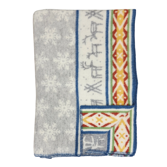 Folded Sámi-inspired wool blanket featuring a gray snowflake pattern, blue border, and one side with geometric and stripe designs in orange, yellow, and blue.