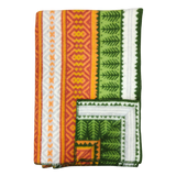 Folded blanket with orange, yellow, green, and white geometric patterns, zigzag designs, and decorative stitched border in Scandinavian style.