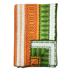 Folded blanket with orange, yellow, green, and white geometric patterns, zigzag designs, and decorative stitched border in Scandinavian style.