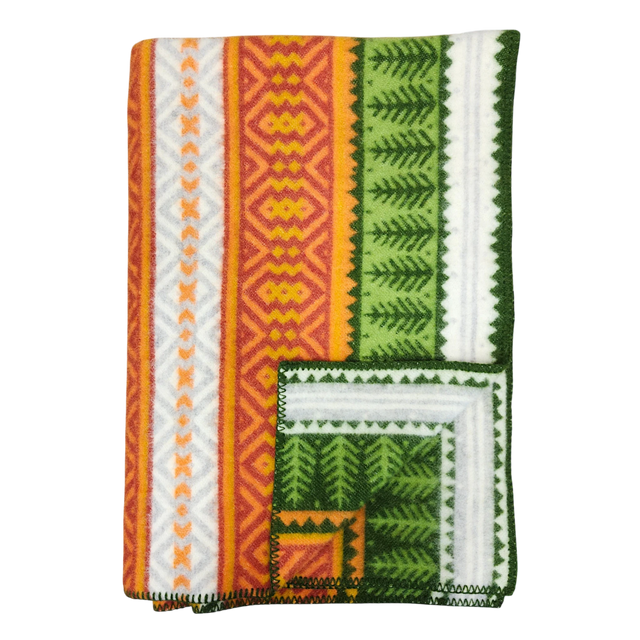Folded blanket with orange, yellow, green, and white geometric patterns, zigzag designs, and decorative stitched border in Scandinavian style.