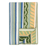 Folded fleece blanket in a Swedish design featuring green, blue, and cream stripes with wavy patterns; one corner is turned over to display the reverse side.