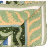 Close-up of a blanket featuring green, beige, and blue Swedish design, with one corner folded to show stitched edges and part of the geometric pattern.