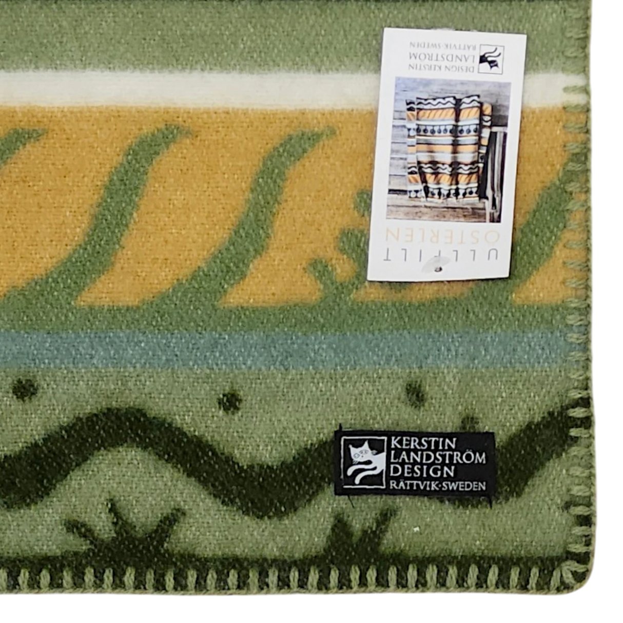 Lambswool blanket with green, beige, and blue stripes. Two visible labels: one product tag and one reading “Kerstin Landström Design Rättvik, Sweden.”.