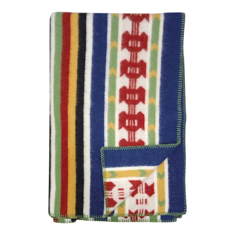 Folded Rättvik wool blanket featuring colorful vertical stripes and geometric patterns; one corner is turned up to show the reverse side.