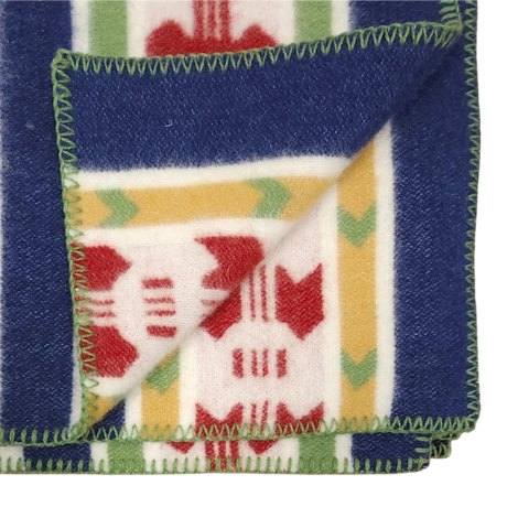 Partially folded blue, cream, and red wool blanket with green-edged stitching, displaying front and back of its Swedish Rättvik pattern.