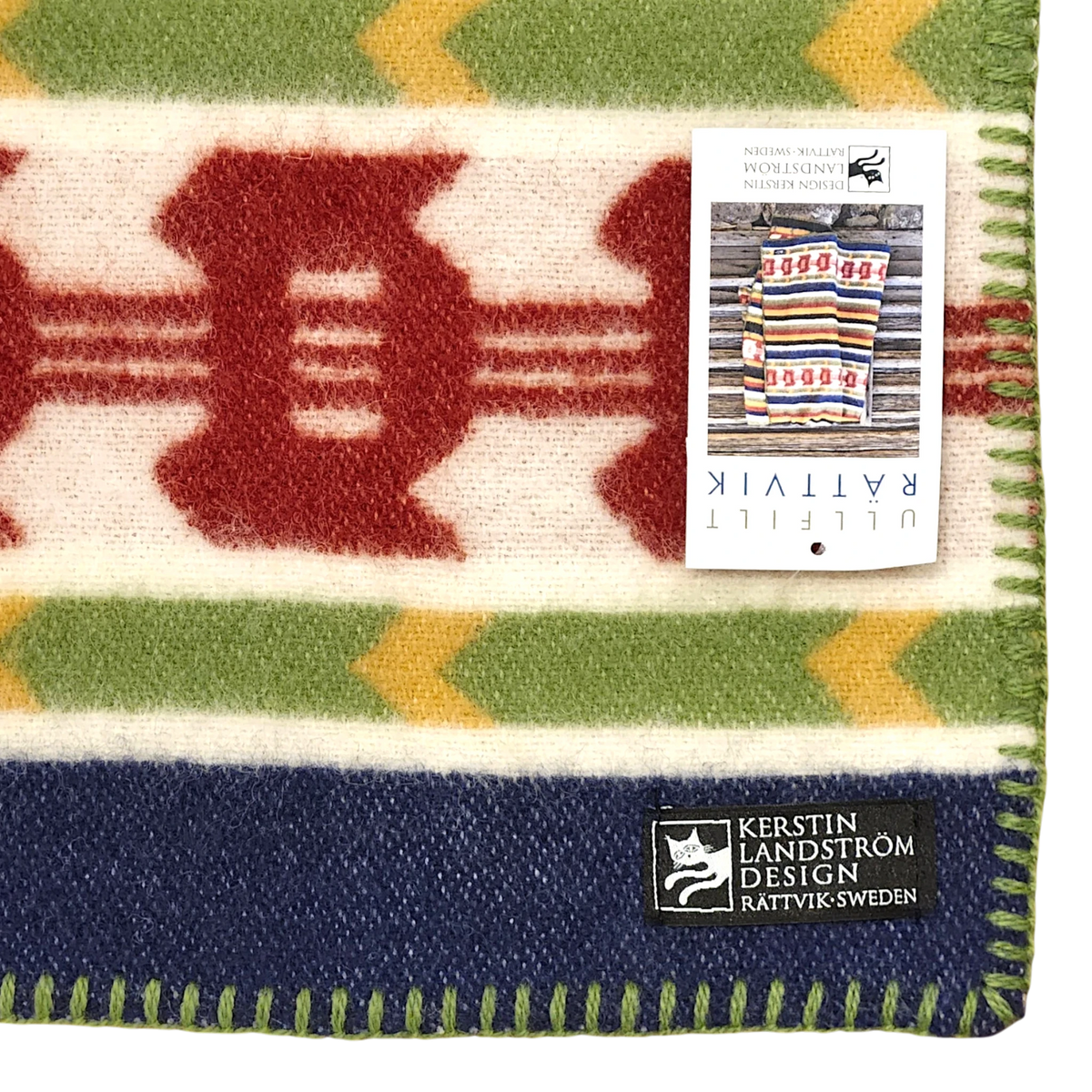 Wool blanket featuring colorful geometric patterns, stitched edges, and a visible Swedish design by Kerstin Landström.