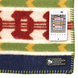 Wool blanket featuring colorful geometric patterns, stitched edges, and a visible Swedish design by Kerstin Landström.