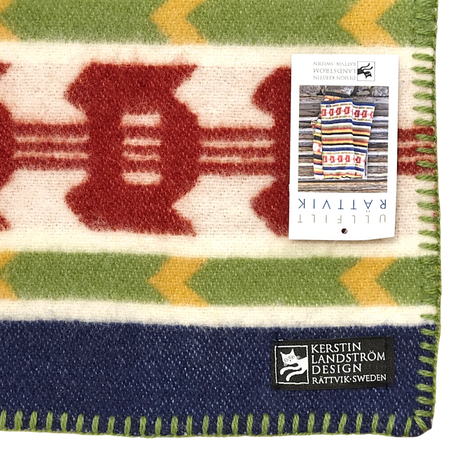 Wool blanket featuring colorful geometric patterns, stitched edges, and a visible Swedish design by Kerstin Landström.