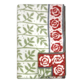 Swedish design blanket featuring green leaf pattern and red rose border on white background; one corner flipped to show reverse side.