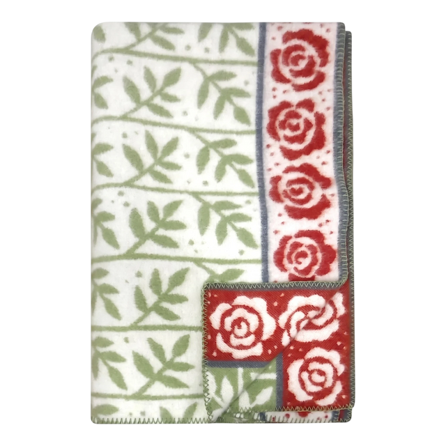 Swedish design blanket featuring green leaf pattern and red rose border on white background; one corner flipped to show reverse side.