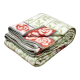 Swedish design blanket with green leaf pattern, red rose-bordered edging, and green and white stitched trim.