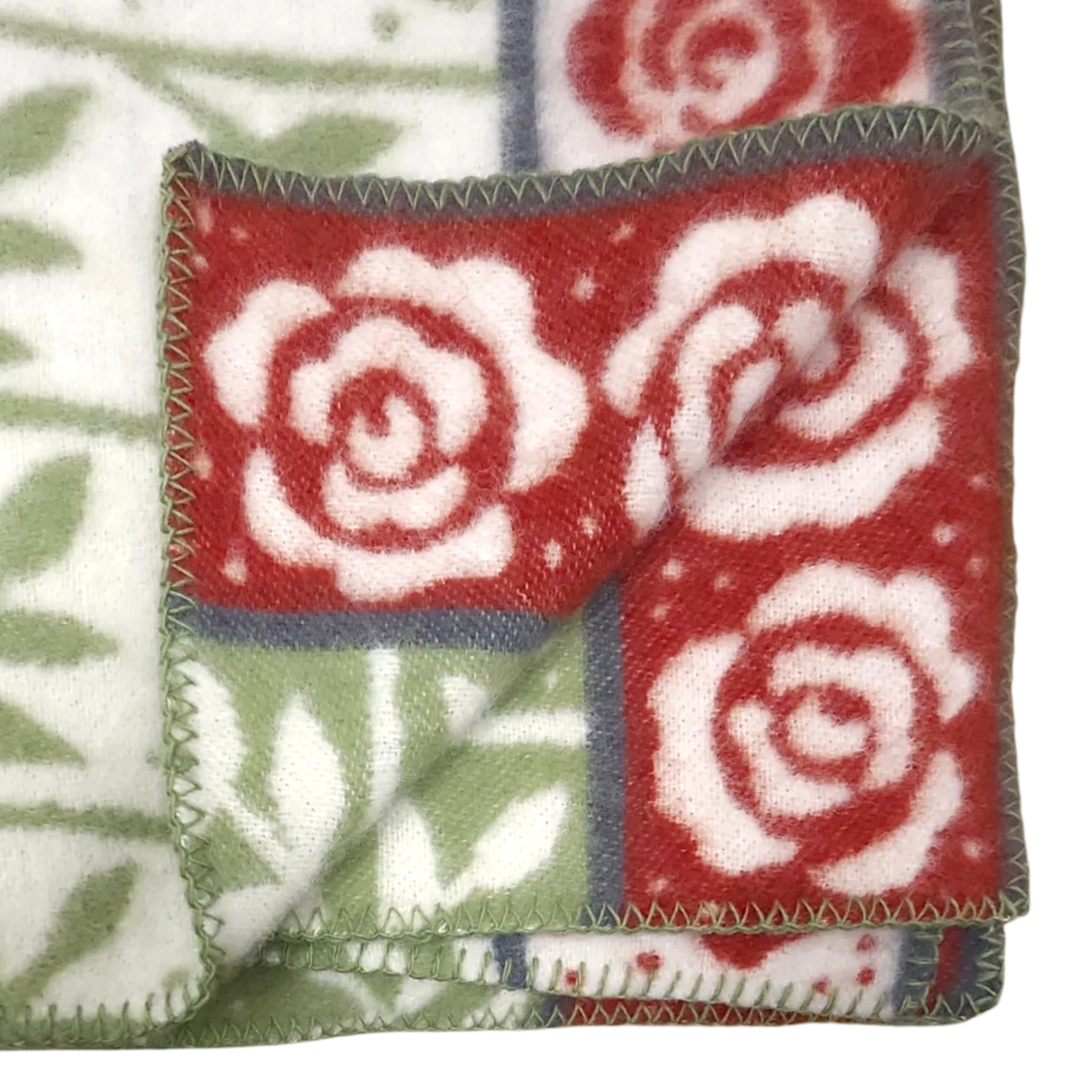 Folded blanket featuring red and white rose patterns, green leaves, visible stitched edges, and floral designs on both sides.
