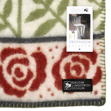 Lambswool blanket featuring red rose patterns with green leaves, plus two visible labels: one reads KERSTIN LANDSTRÖM DESIGN; the other shows product image and details.